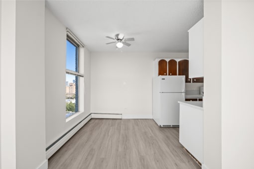 an empty living room with a large window and a kitchen