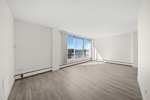 an empty living room with wood flooring and a large window