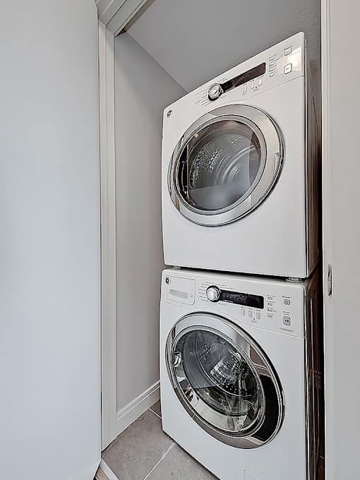 Two white front loading washing machines in a small laundry room.