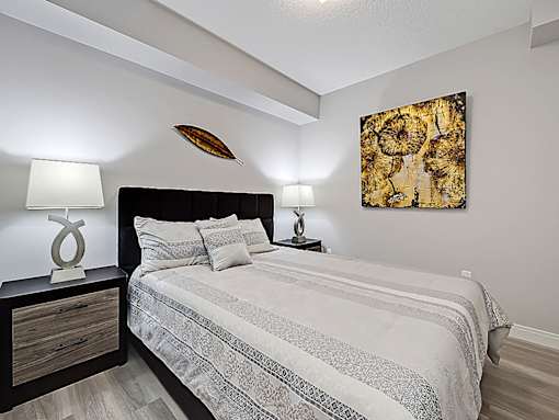 A bedroom with a bed, nightstand, and a painting on the wall.