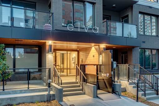 The entrance to a modern building with a glass door and a staircase leading up to it.