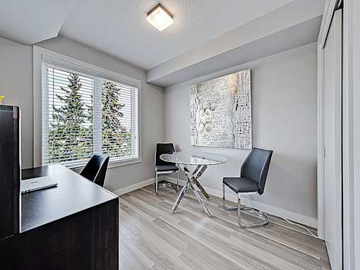 A room with a desk, chairs, and a painting on the wall.