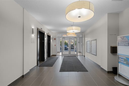 a hallway with doors and rugs in a building with white walls