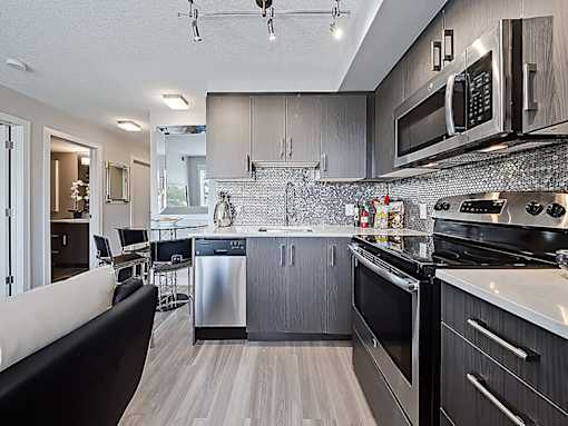 A modern kitchen with dark wood cabinets and stainless steel appliances.