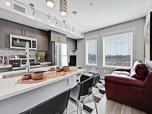 A modern kitchen with a red couch and black chairs.