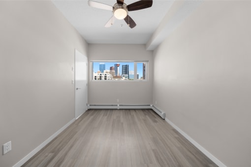 an empty living room with a ceiling fan and a window