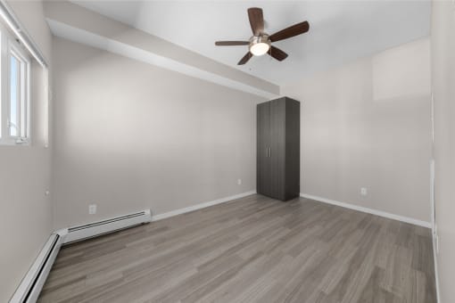 an empty living room with a ceiling fan and a closet