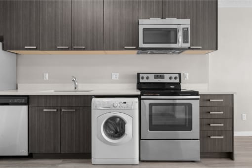 a kitchen with stainless steel appliances and a washing machine and a microwave