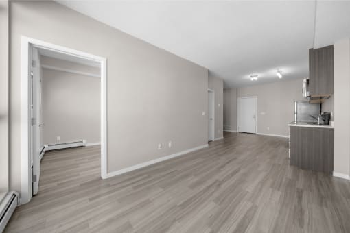 the living room and dining room of an apartment with wood flooring and white walls