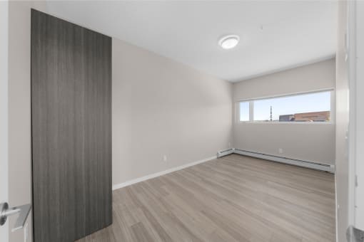 an empty living room with wood flooring and a window