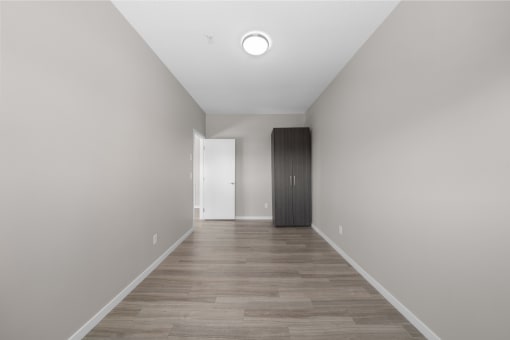 a long hallway with white walls and wood floors and a closet