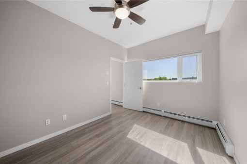 an empty living room with a ceiling fan and a window