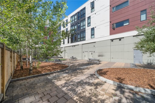 a courtyard with benches and trees in front of a building