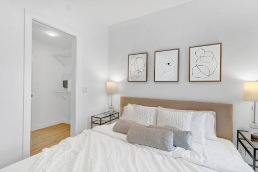 A bedroom with a large bed and three framed artworks on the wall.