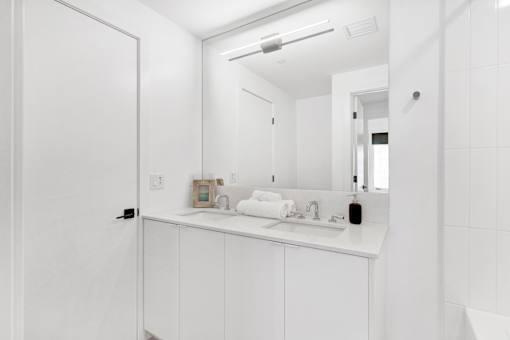 A white bathroom with a sink and mirror.
