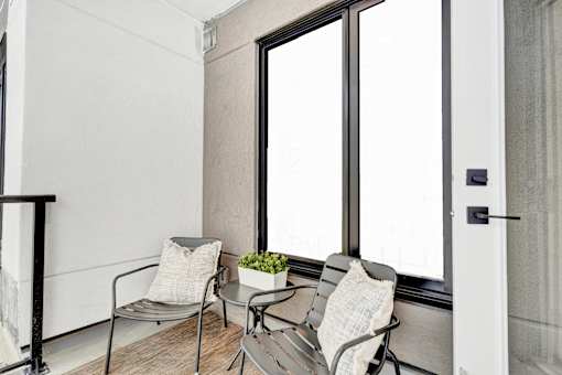 A small balcony with two chairs and a table.