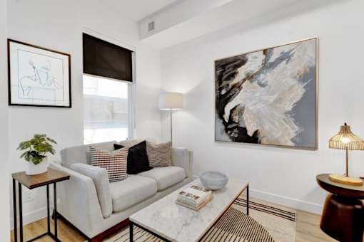 A living room with a grey couch, a coffee table, a side table, a lamp, and a painting on the wall.