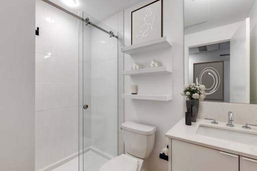 A white bathroom with a toilet, sink, and shower.
