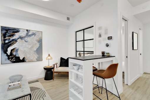 A modern living room with a large abstract painting on the wall, a black and white sofa, a coffee table, and a black floor lamp.