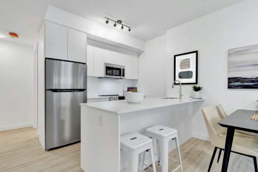 A modern kitchen with white cabinets and a stainless steel refrigerator.