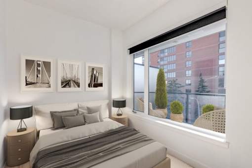 A bedroom with a large bed and a window overlooking a cityscape.