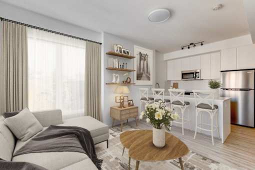 A modern living room with a grey sofa, a wooden coffee table, and a kitchen area in the background.