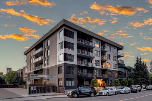 A large apartment building with cars parked in front.