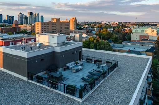 A rooftop patio with a table and chairs overlooks a city skyline.