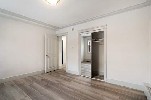 A room with a white door and a mirror on the wall.