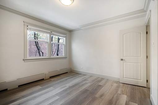 A room with a white door and a window with a view of trees.