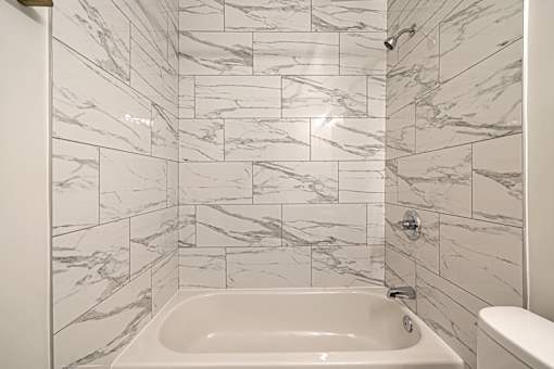 A white bathroom with a marble tile wall.