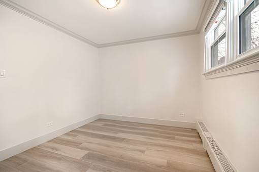 A room with a window and a wooden floor.
