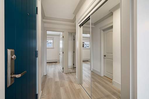 A hallway with a blue door and a mirror on the wall.