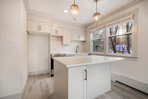 A kitchen with white cabinets and a marble countertop.