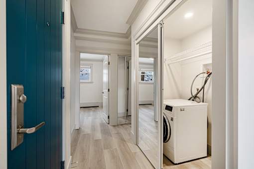 A hallway with a washing machine in the doorway.