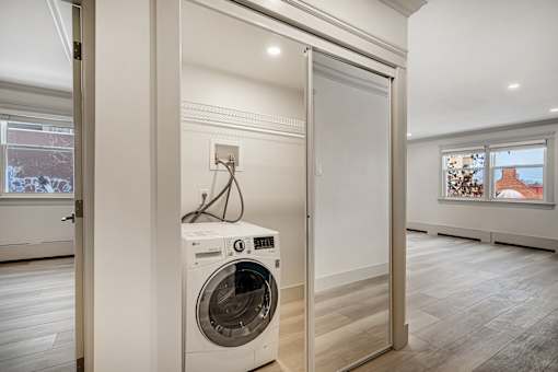 A white washing machine is in a small room with a door open.