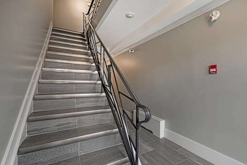 A staircase with a metal railing and grey steps.