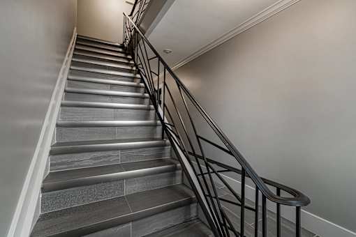 A staircase with a black metal railing and grey steps.