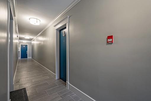 A hallway with a blue door and a red sign on the wall.