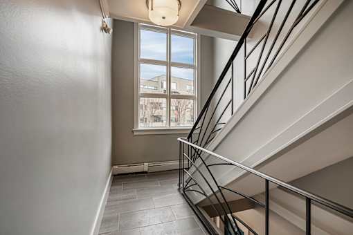 A staircase with a metal railing and a window overlooking a building.
