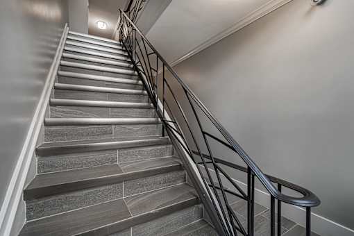 A staircase with a metal railing and stone steps.
