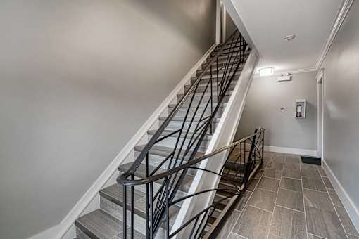 A staircase with a metal railing and steps made of stone or tile.