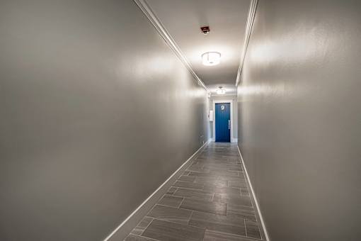 A long hallway with a blue door at the end.