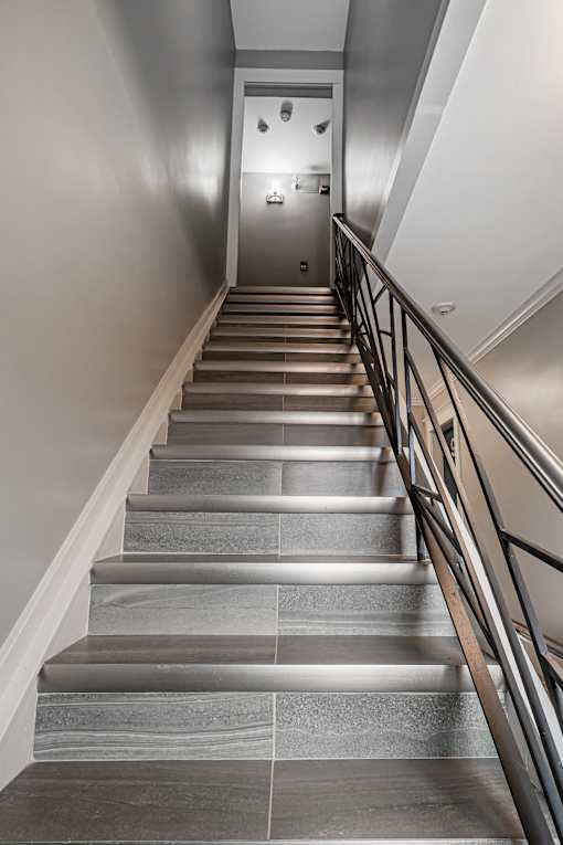 A staircase with a metal railing and stone steps leading to a door.