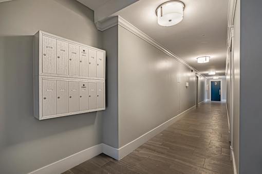 A long hallway with a cabinet on the wall and a door at the end.