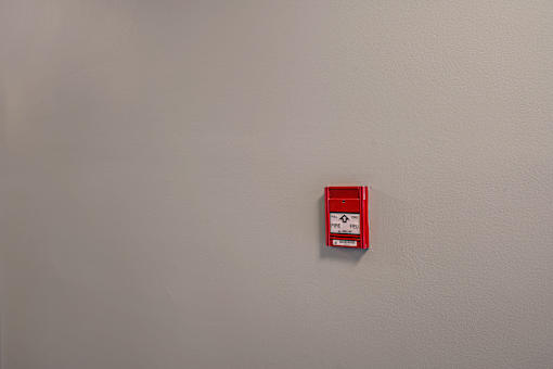 A red fire alarm on a white wall.