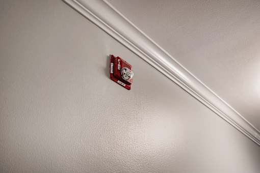 A red fire alarm on a white wall.