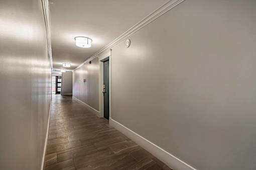 A long hallway with a wooden floor and white walls.