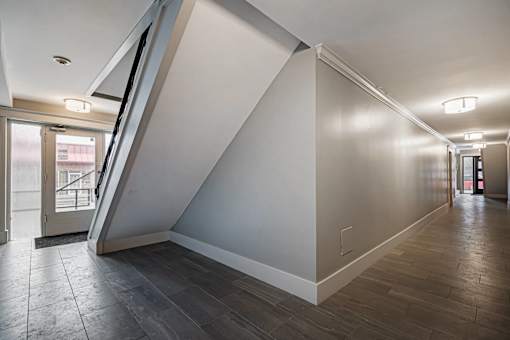 A hallway with a staircase on the left side and a door on the right side.