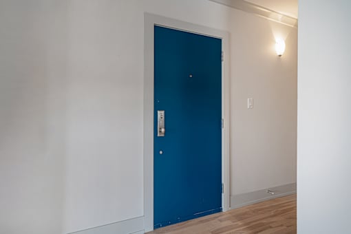 A blue door in a room with white walls.